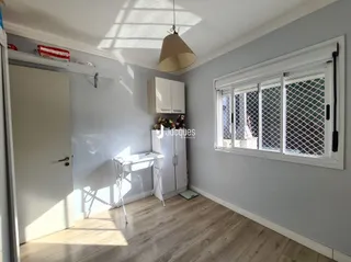 Ambiente interno de uma sala com piso de madeira e janela.