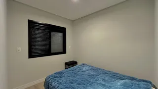 Quarto com cama grande e janela com persiana escura.