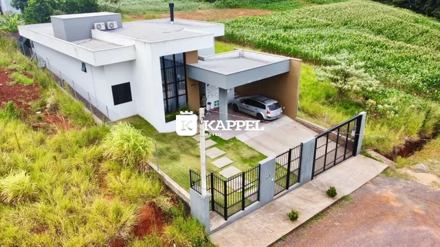 Fachada de uma casa moderna em Lajeado, Brasil, com área de garagem coberta e jardim ao redor.