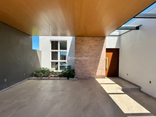 Área externa pavimentada com teto de madeira e parede branca.