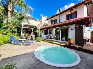 Vista externa de uma piscina com deck e jardim.