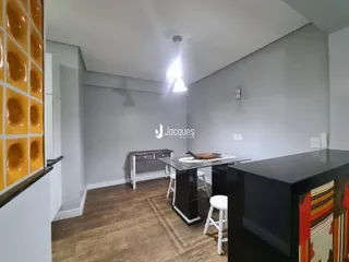 Interior de uma sala com piso de madeira e bancada moderna.