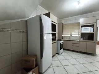 Interior de uma cozinha com armários e geladeira em um imóvel no Brasil.