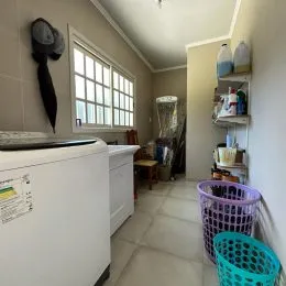 Foto de uma área de serviço com máquina de lavar e piso de cerâmica.