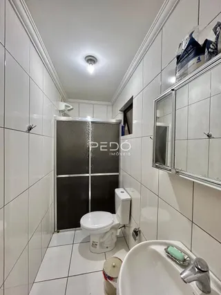 Foto de um banheiro com revestimento de cerâmica branca e louças sanitárias.