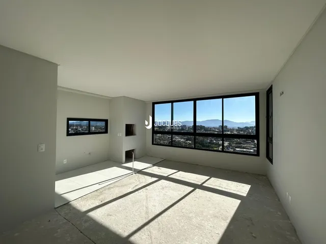 Ambiente interno de uma sala com piso de concreto e grande janela em Lajeado.