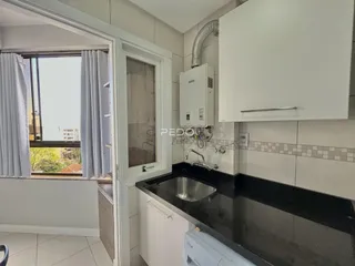 Vista da cozinha com armários brancos e bancada escura.