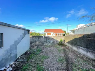 Vista externa de uma propriedade com muro e terreno.
