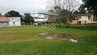 Vista externa de uma propriedade com um grande gramado molhado em primeiro plano.
