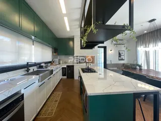 Cozinha moderna com armários verdes e ilha de mármore.