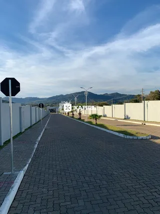 Vista externa de uma rua pavimentada com muros laterais brancos.