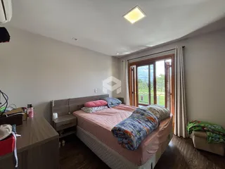 Quarto com cama e janela de madeira no interior da residência.