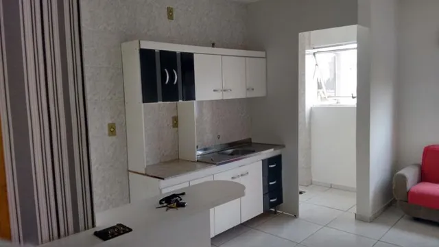 Armários brancos de cozinha com bancada em um imóvel.