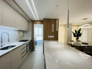 Vista de uma cozinha moderna e área de estar em um apartamento.
