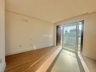 Sala de estar com piso de madeira e porta de vidro que dá para a vista.