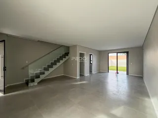 Vista interna de um ambiente amplo com escadaria e portas de vidro.