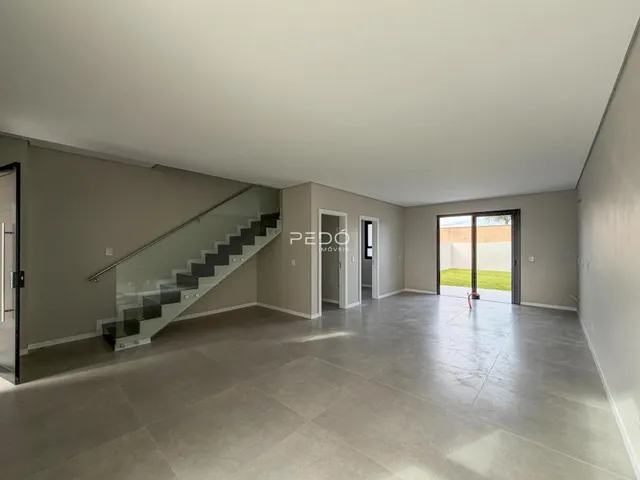 Vista interna de um ambiente amplo com escadaria e portas de vidro.