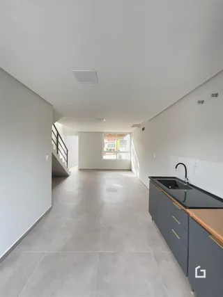 Corredor interno de uma residência com piso claro e paredes brancas.