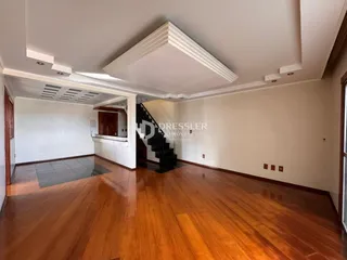 Interior de uma sala ampla com piso de madeira polida.