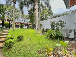 Vista externa de um jardim gramado com árvores e cerca em Lajeado.