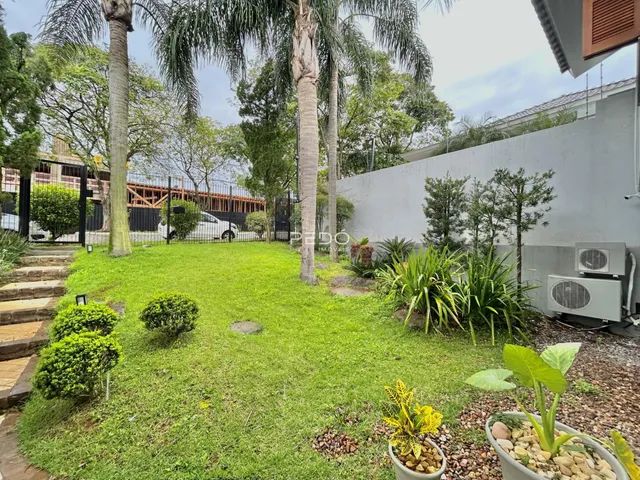 Vista externa de um jardim gramado com árvores e cerca em Lajeado.
