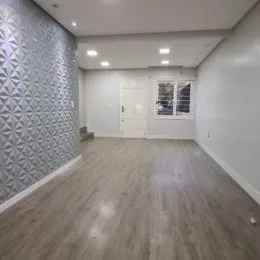 Foto de um ambiente interno com piso de madeira clara e paredes brancas.