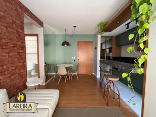 Interior de uma sala de estar com piso de madeira e área de jantar.