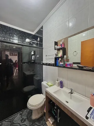 Foto interna de um banheiro com revestimentos de azulejo e bancada branca.