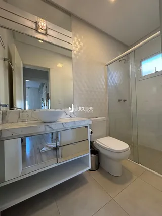 Banheiro moderno com bancada de mármore e box de vidro.