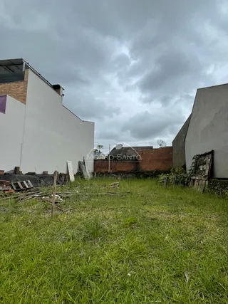 Vista externa de uma propriedade com grama alta e estruturas em construção.