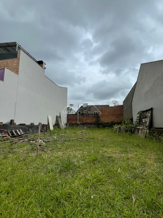 Vista externa de uma propriedade com grama alta e estruturas em construção.