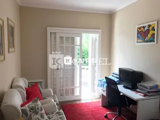 Foto interna de uma sala de estar com sofá e televisão.