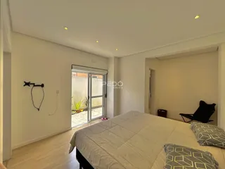 Quarto com piso de madeira e porta de vidro de acesso ao exterior.