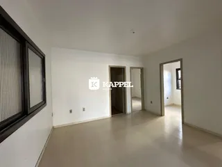 Sala de estar com piso claro e paredes brancas em um imóvel.