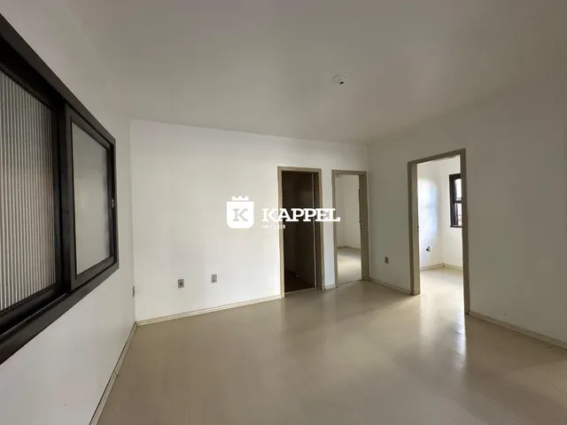 Sala de estar com piso claro e paredes brancas em um imóvel.