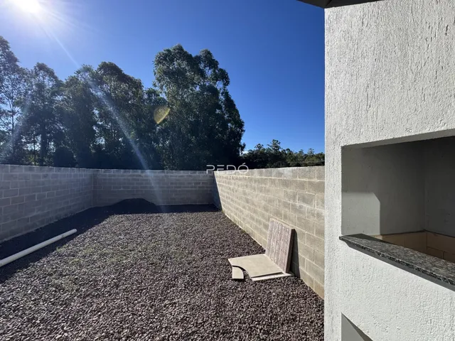 Vista externa de um pátio com piso de cascalho e muros de alvenaria.