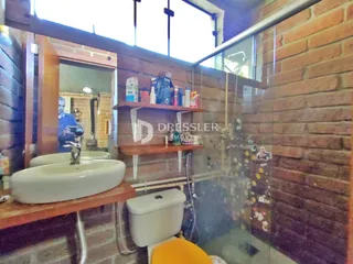 Foto de um banheiro com pias brancas e revestimento de tijolo aparente.
