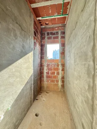 Uma passagem estreita com paredes de concreto e tijolo exposto.