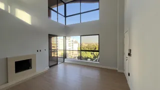Uma sala de estar ampla com grandes janelas que oferecem uma vista da paisagem urbana.