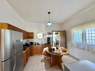 Foto da cozinha com armários de madeira e mesa de jantar.