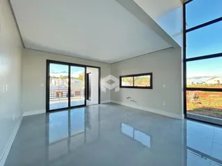 Sala de estar com piso de alto brilho e grandes janelas que dão vista para o exterior.