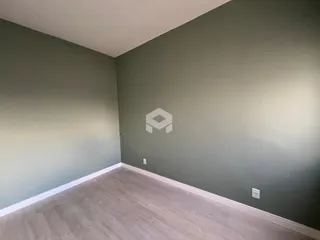 Parede interna de uma sala com piso de madeira clara e pintura verde-acinzentada.