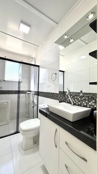 Foto interna de um banheiro com revestimento cerâmico branco.