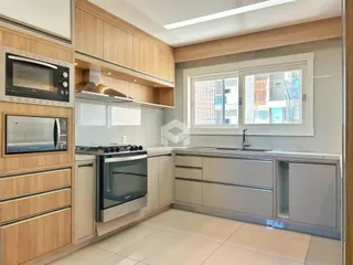 Cozinha moderna com armários de madeira e bancadas claras.