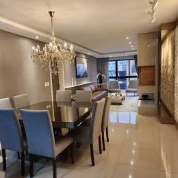 Sala de jantar com mesa e lustre de cristal em ambiente interno.