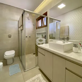 Foto de um banheiro moderno com box de vidro e bancada clara.