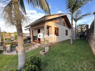 Fachada de uma casa térrea com jardim gramado e palmeiras em Lajeado, Brasil.