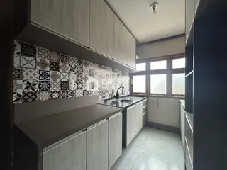 Vista de uma cozinha com armários e revestimento de azulejos na Lajeado.