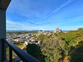 Vista panorâmica da paisagem urbana de Lajeado, Brasil, com vegetação no primeiro plano.