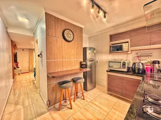 Interior de uma cozinha e sala de estar com armários de madeira e piso de cerâmica.